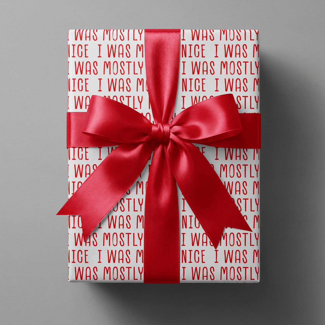 Naughty christmas wrapping paper with repeating bold red "I was mostly nice" text on white.