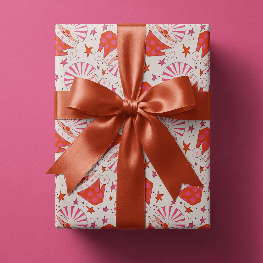 Red and pink christmas wrapping paper with pinwheel Santa hats and stars on cream.