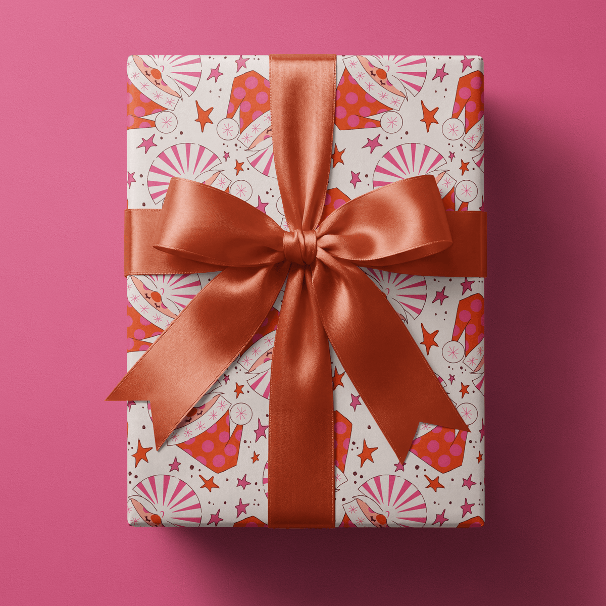 Red and pink christmas wrapping paper with pinwheel Santa hats and stars on cream.