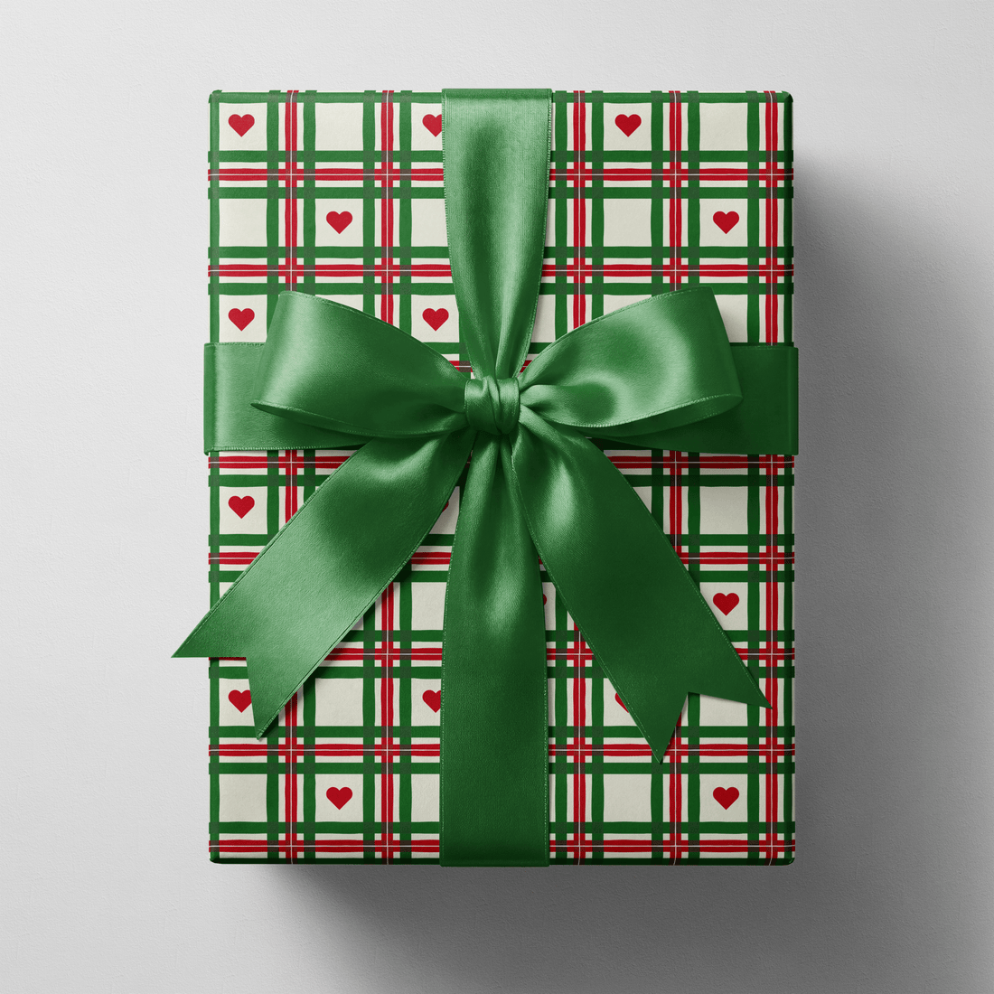 Plaid christmas wrapping paper with hand-drawn green and red lines and small red hearts.