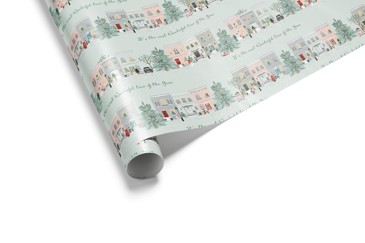 Rolled wrapping paper featuring illustrated pastel townhouses on a mint holiday background