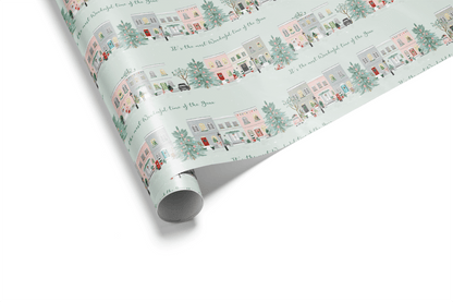 Rolled wrapping paper featuring illustrated pastel townhouses on a mint holiday background