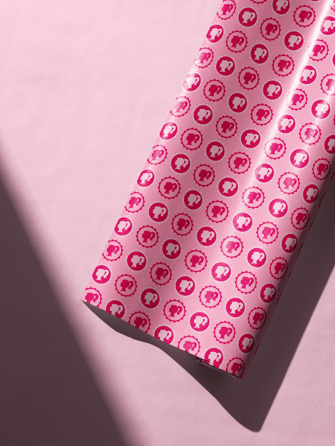 Vibrant pink Barbie wrapping paper roll featuring repeating doll silhouettes, ideal for birthday and Christmas gifts.