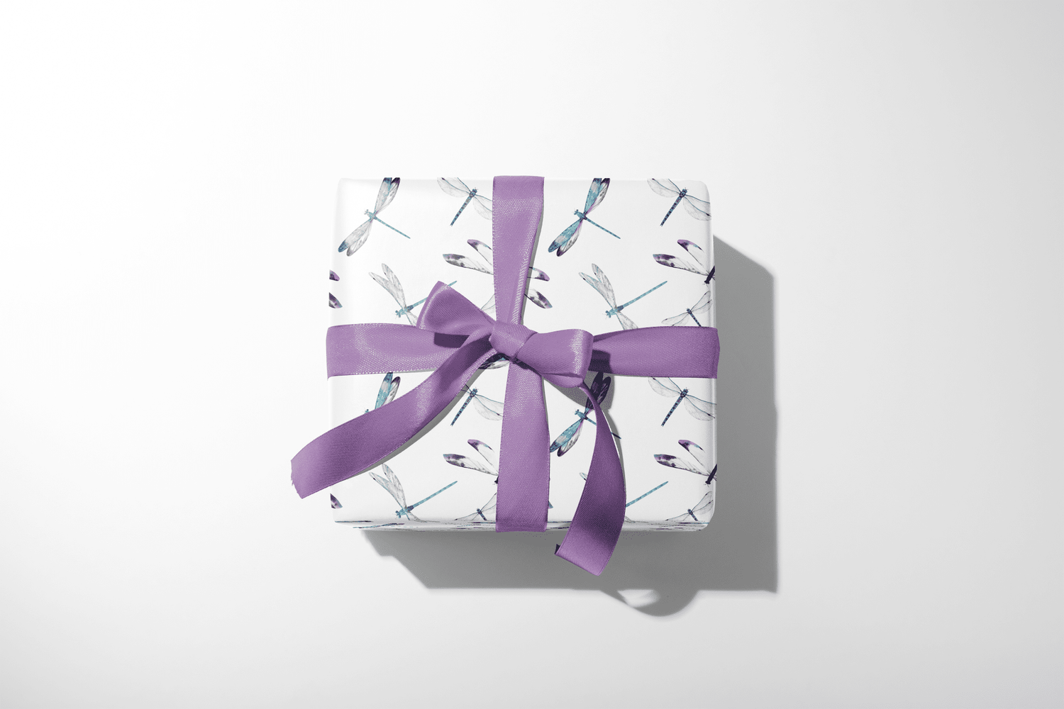 Dragonfly Themed Gift Wrap Paper on wrapped gift box with purple ribbon, gossamer flight dragonfly pattern on white