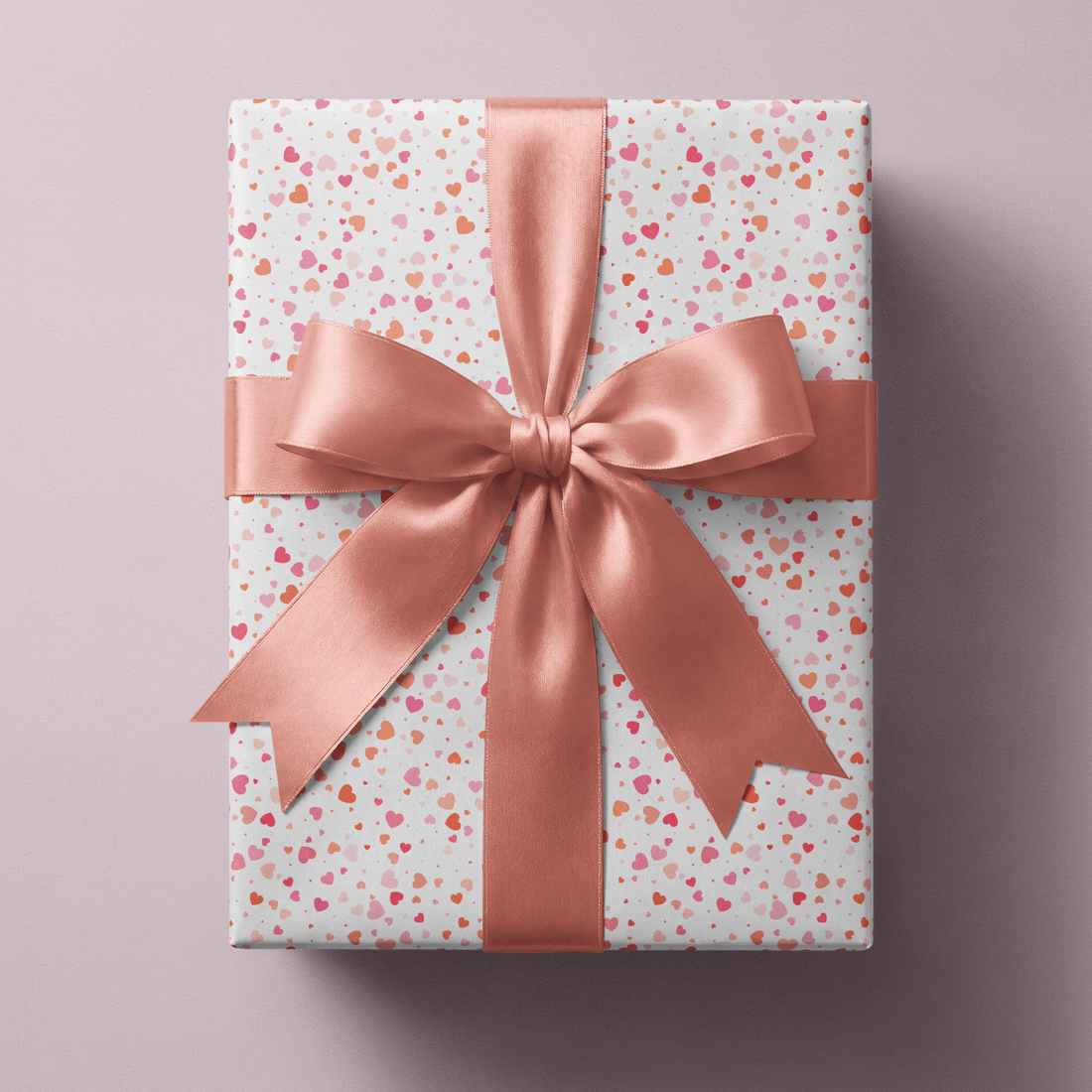 Haus of Wrap heart print gift wrap with pink satin bow, perfect for birthday, wedding, or holiday gifts on mauve background.