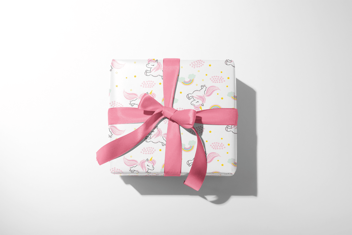 Unicorn Wrapping Paper on gift box with pink ribbon, pastel unicorns, rainbows and gold stars for Sparkle Dream Parade
